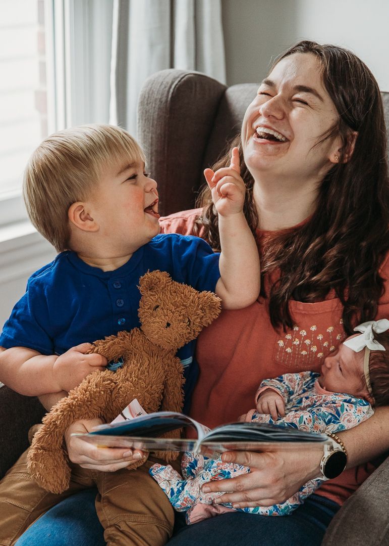 A joyful moment reading together with a teddy bear and book on a cozy chair.