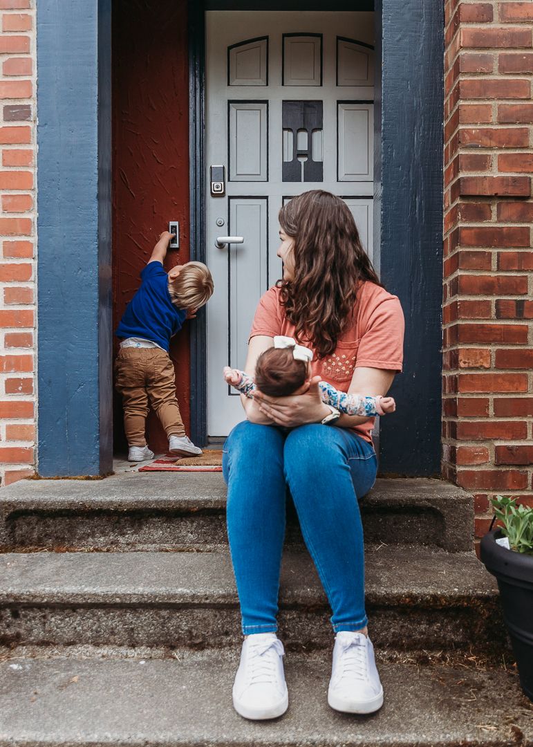 A tender moment on front steps of a brick house with children exploring.