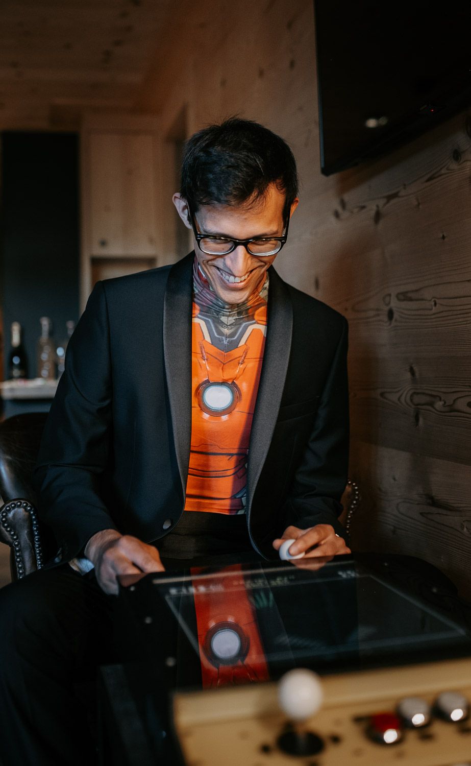 Elegantly dressed man in black tuxedo with orange novelty tie uses tablet at wedding reception.