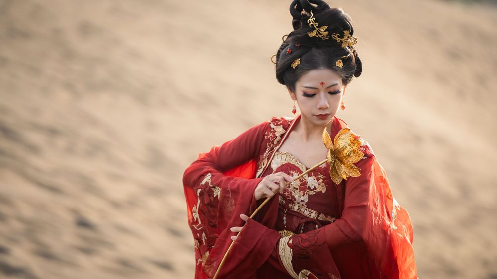 Cinematic solo portrait in flowing red Hanfu at Lake Wainamu sand dunes, evoking a fateful Desert Princess vibe, by Imagine Image Studio.