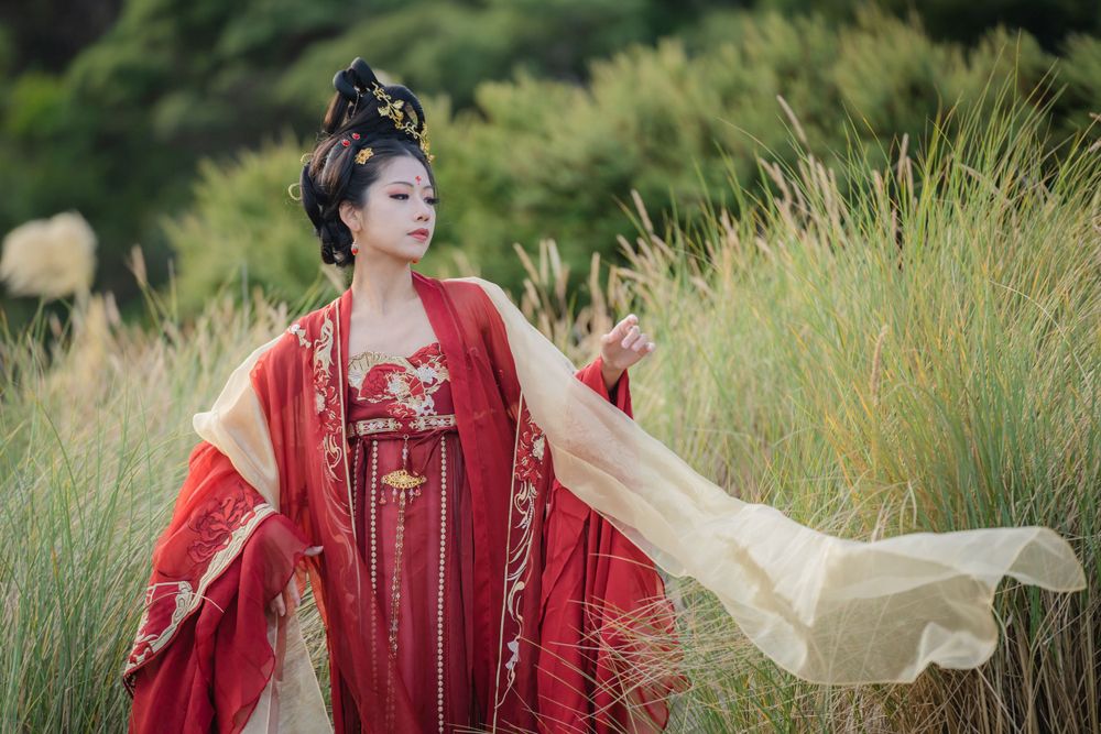 Cinematic solo portrait in flowing red Hanfu at Lake Wainamu sand dunes, evoking a fateful Desert Princess vibe, by Imagine Image Studio.