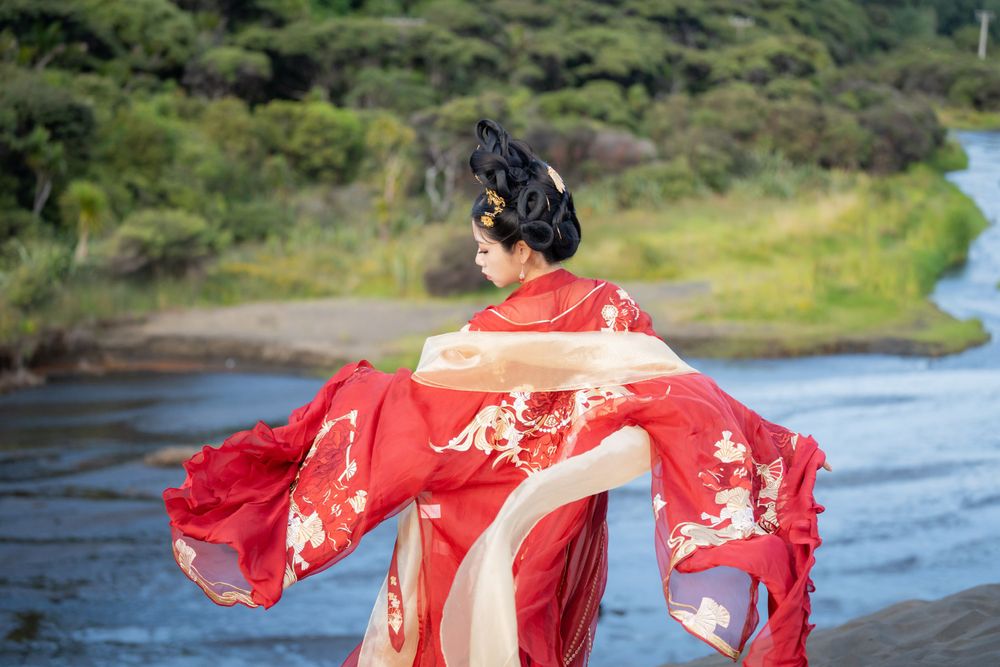 Cinematic solo portrait in flowing red Hanfu at Lake Wainamu sand dunes, evoking a fateful Desert Princess vibe, by Imagine Image Studio.
