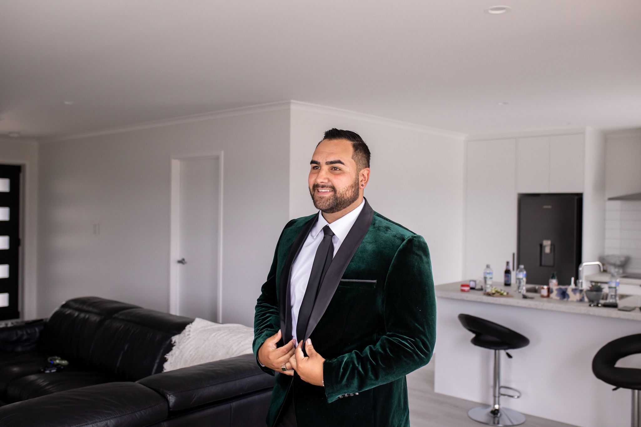 A person wearing an elegant emerald green velvet suit jacket in a modern interior setting.