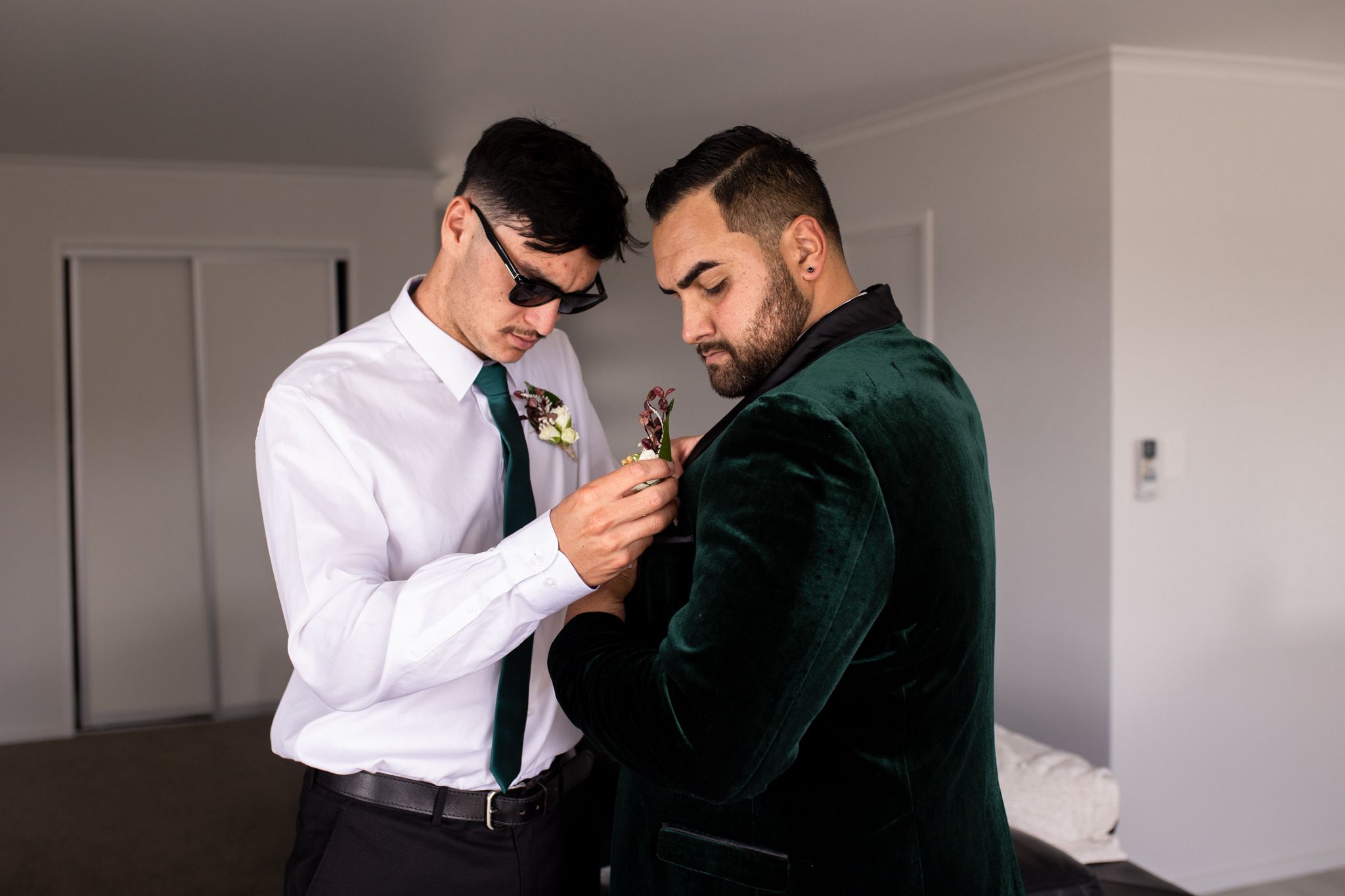 Two people in formal attire examining something on a phone in a bright room.