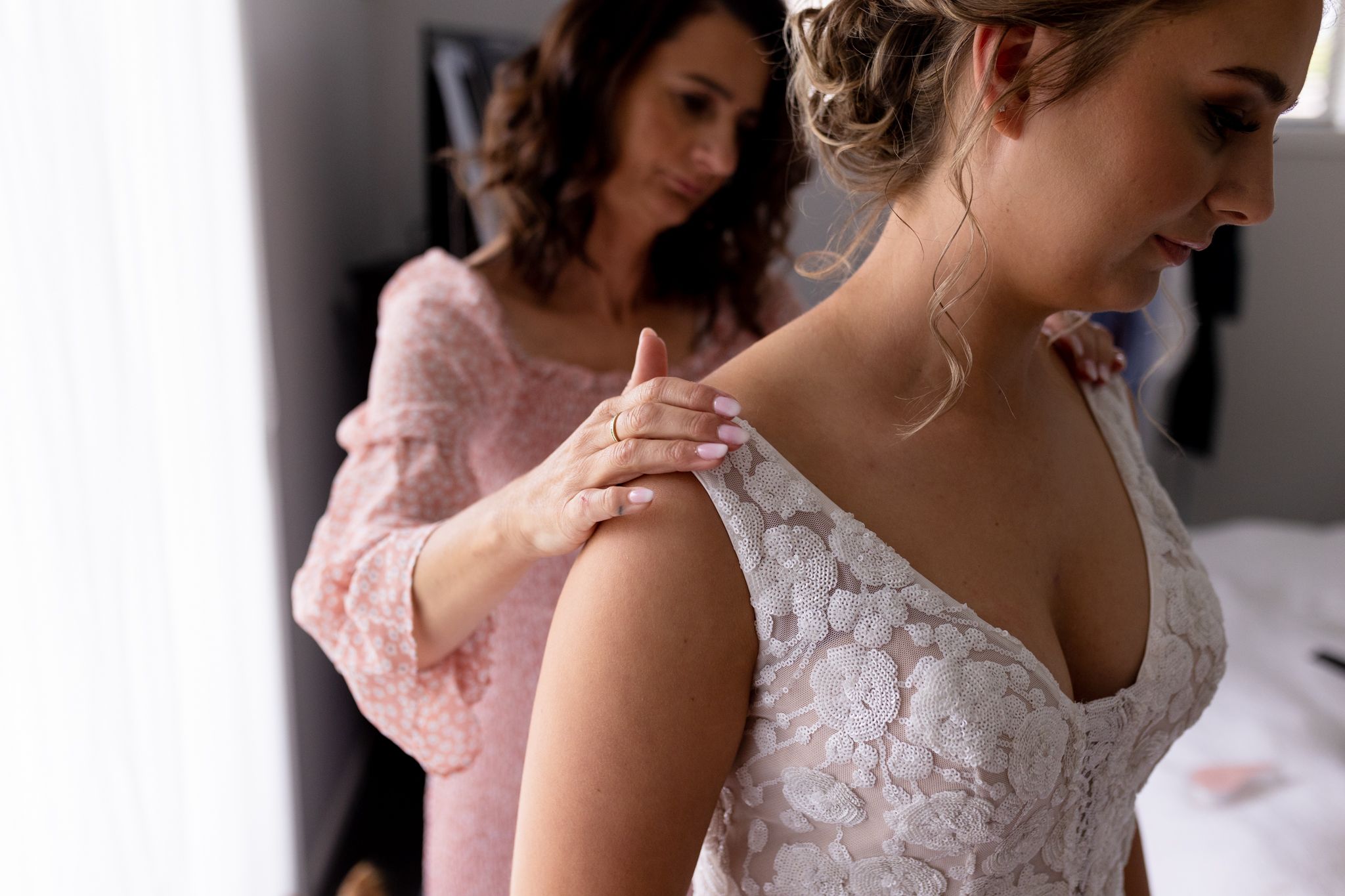 Final touches being made to a wedding dress in soft natural window light.