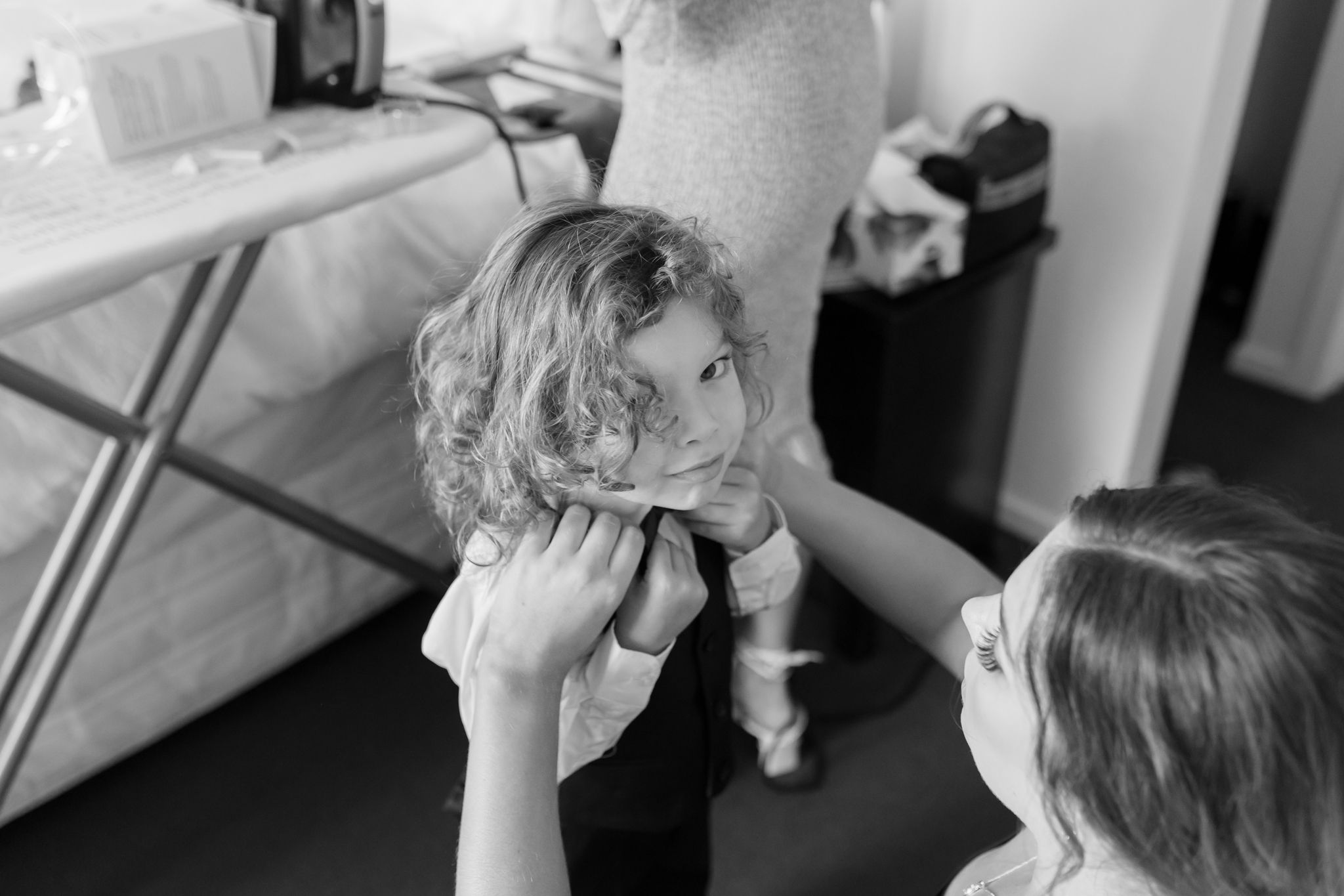 Black and white candid photo of a child getting hair styled before an event.
