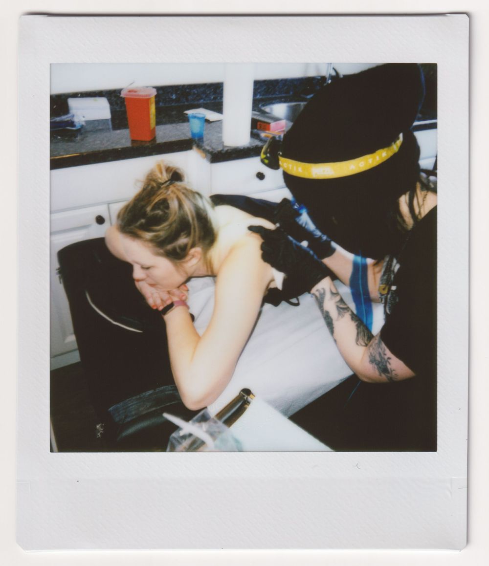 Tattoo artist at work in a studio setting with professional equipment.