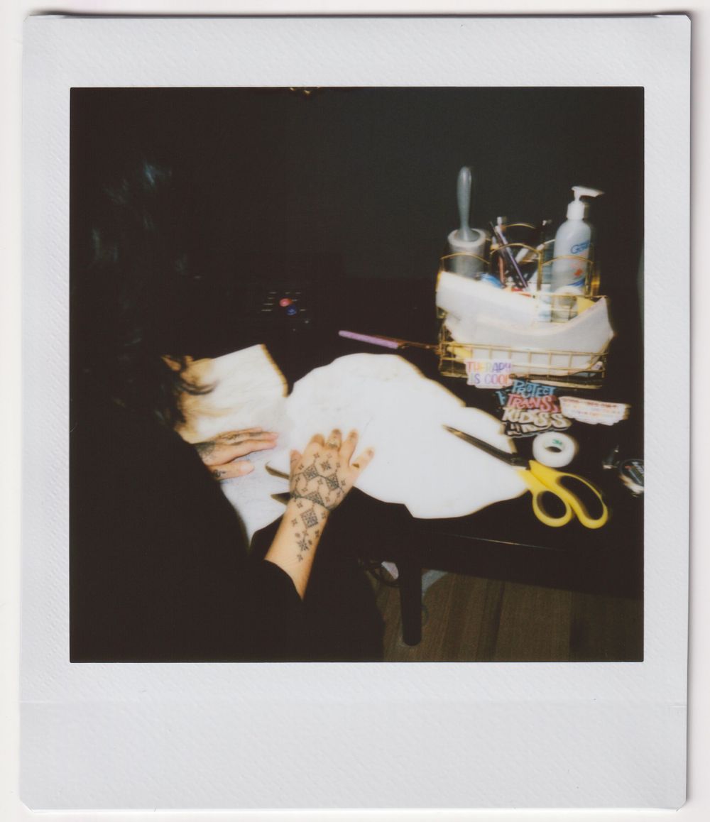 Tattoo supplies and equipment arranged on a dark surface with white cloth and scissors.