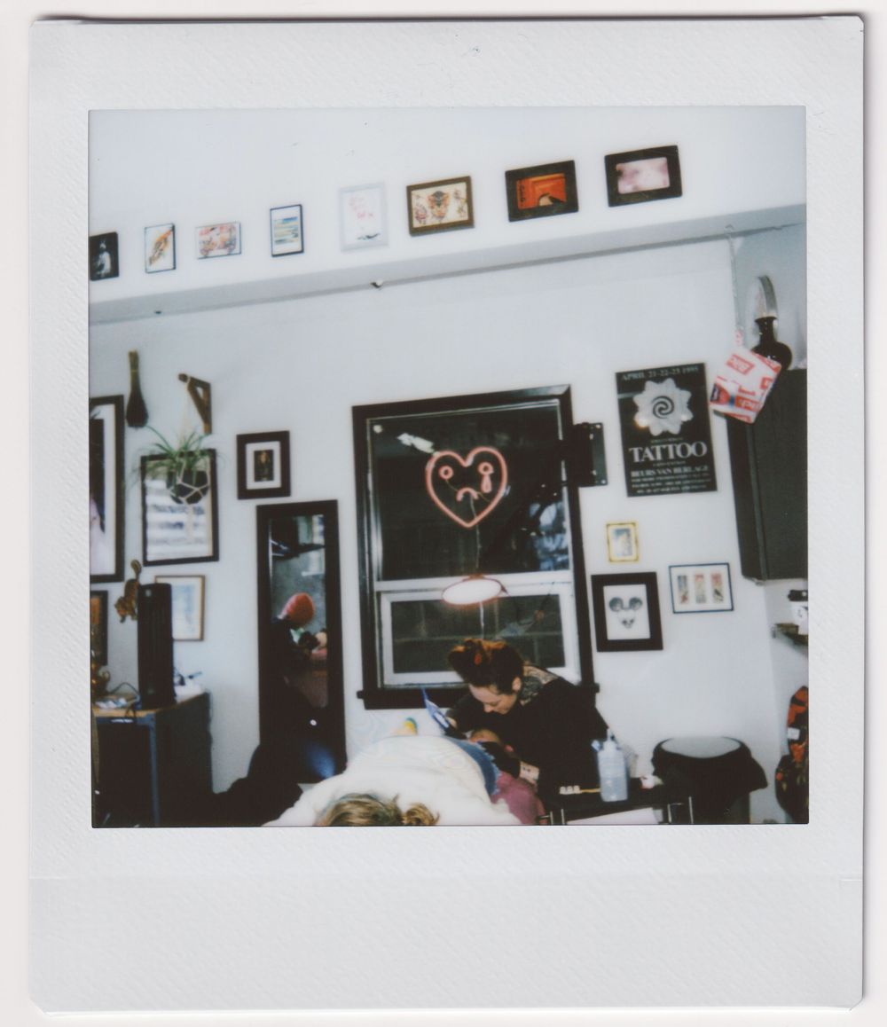 Interior of a tattoo studio with framed artwork and heart design on the walls.