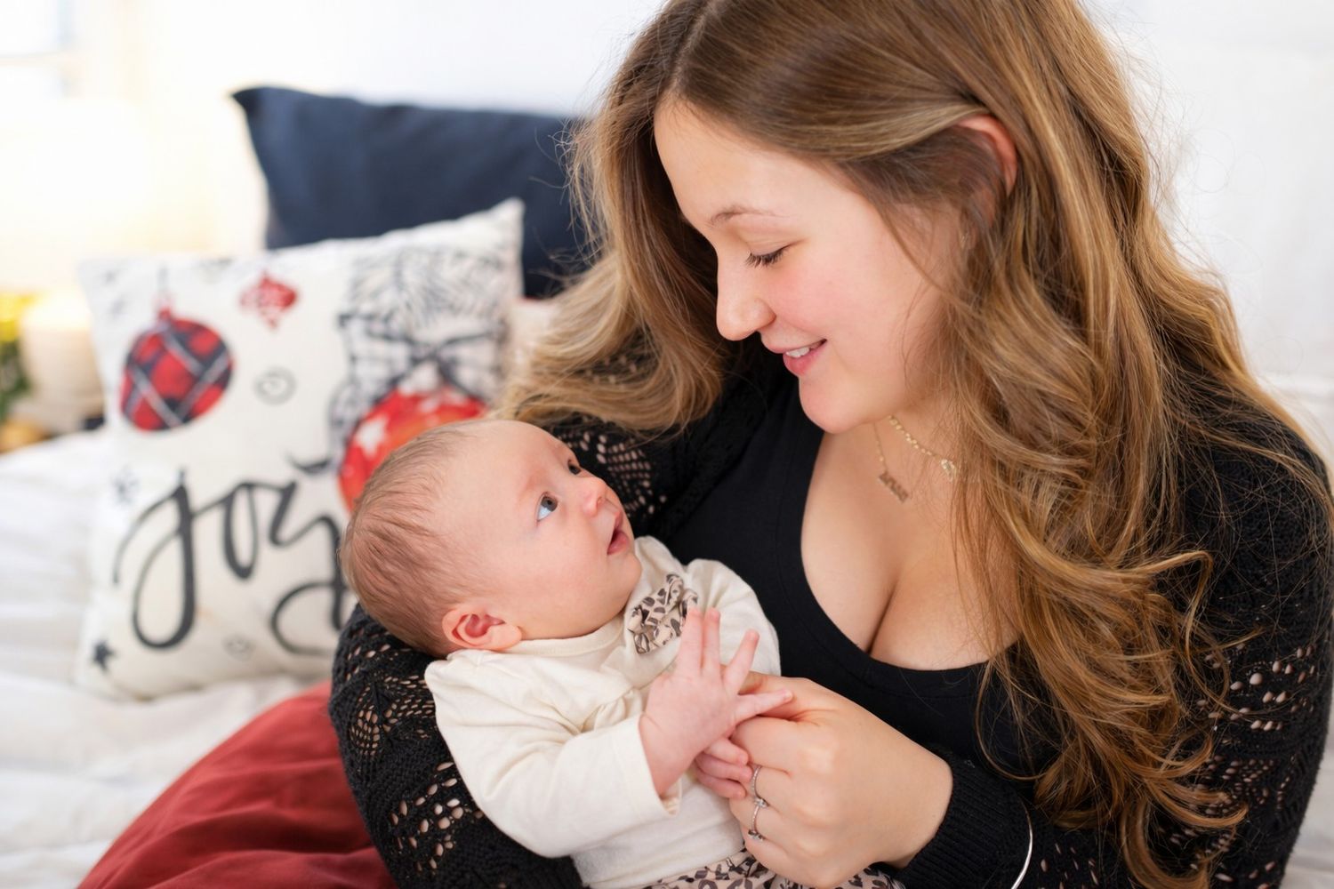 A sweet holiday portrait moment with soft focus and Christmas decorations glowing in the background.