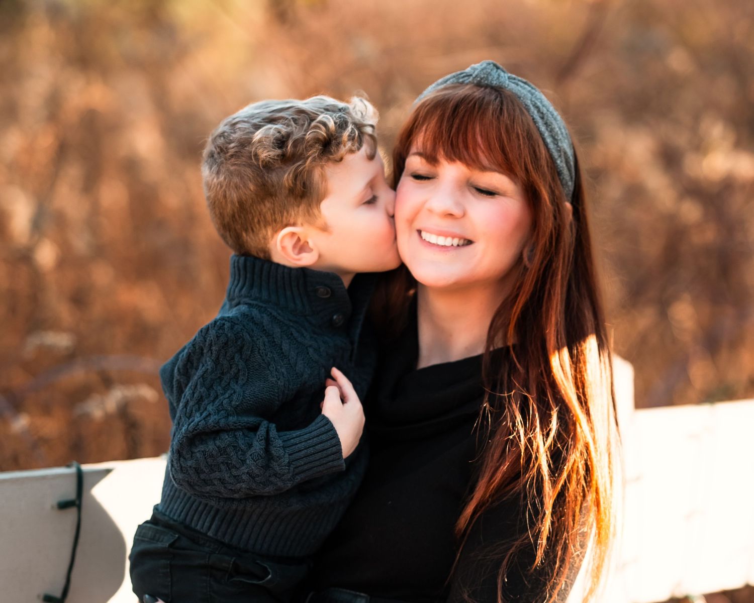 A couple embraces and shares tender moments against an autumn backdrop with warm lighting.
