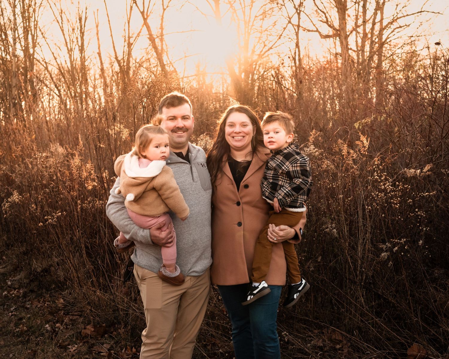 A group of people share joyful moments together during a sunset photoshoot in a rustic outdoor setting.