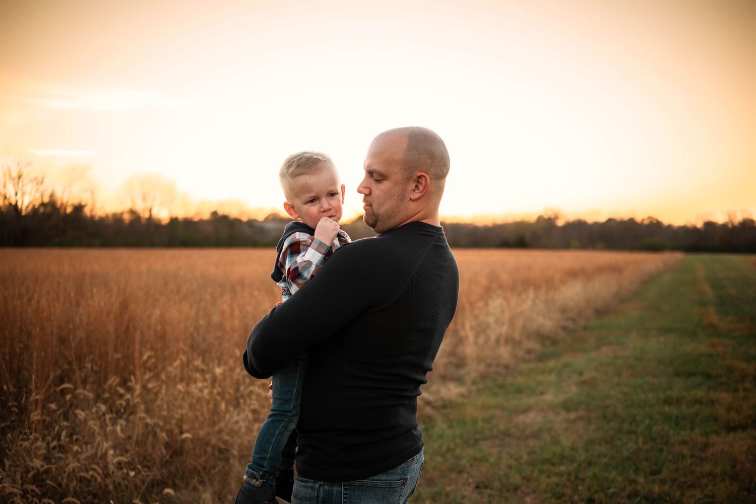 Candid family photos taken at sunset in a golden field showing joyful interactions.