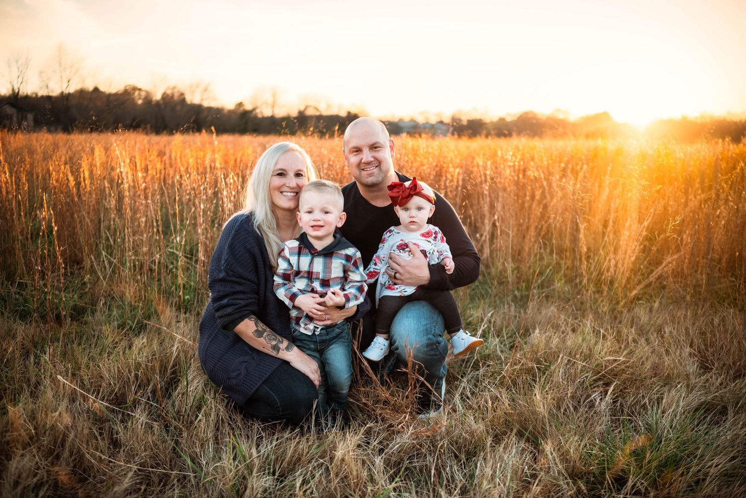 Family portrait session in golden field during magical sunset hour.