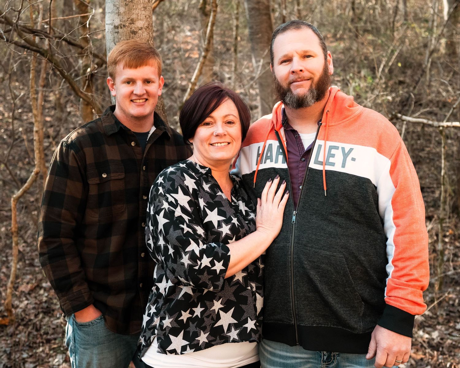 Group photo of family members wearing casual attire in a natural wooded setting.
