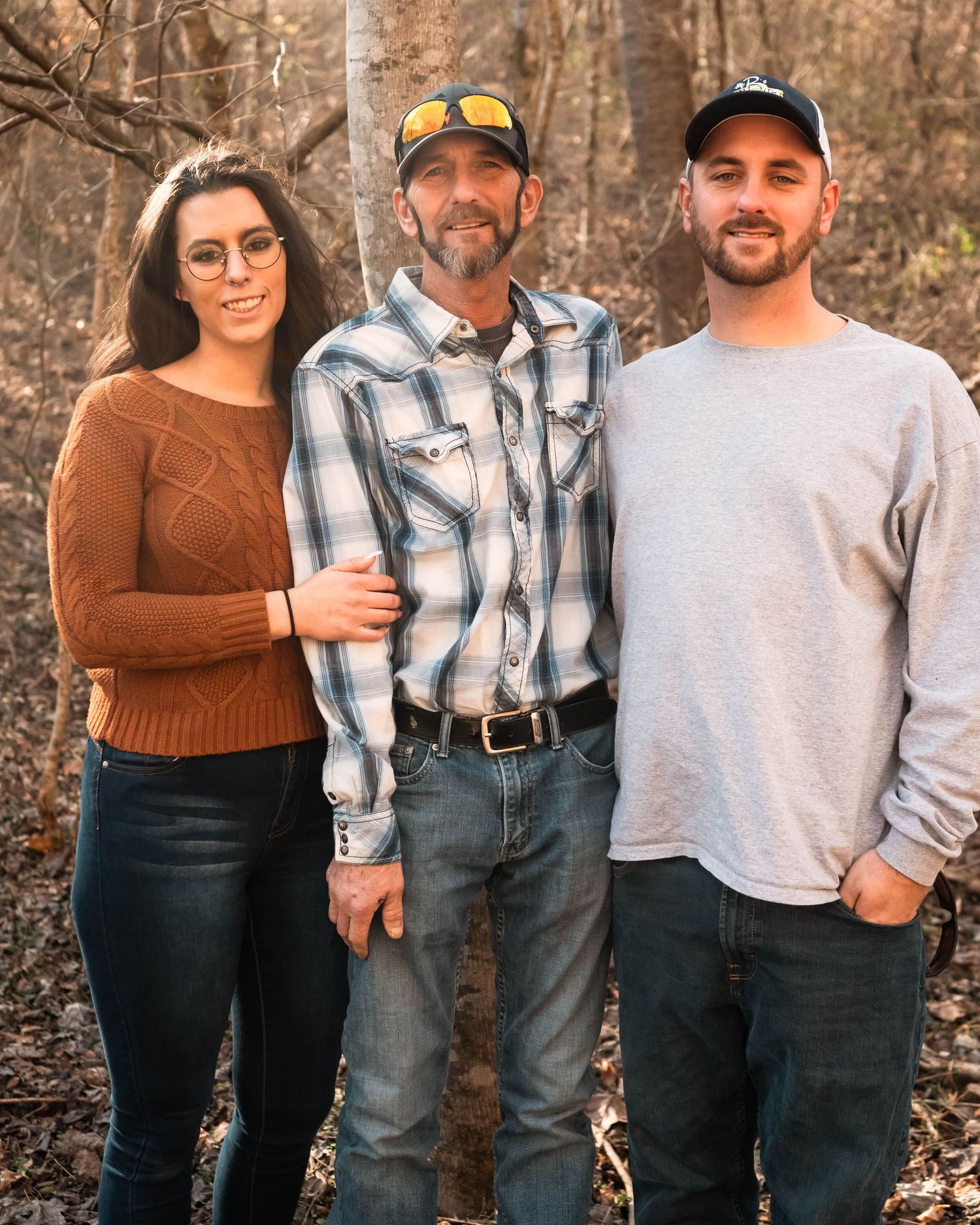 Family members lined up against rustic woodland backdrop wearing coordinated casual clothing.