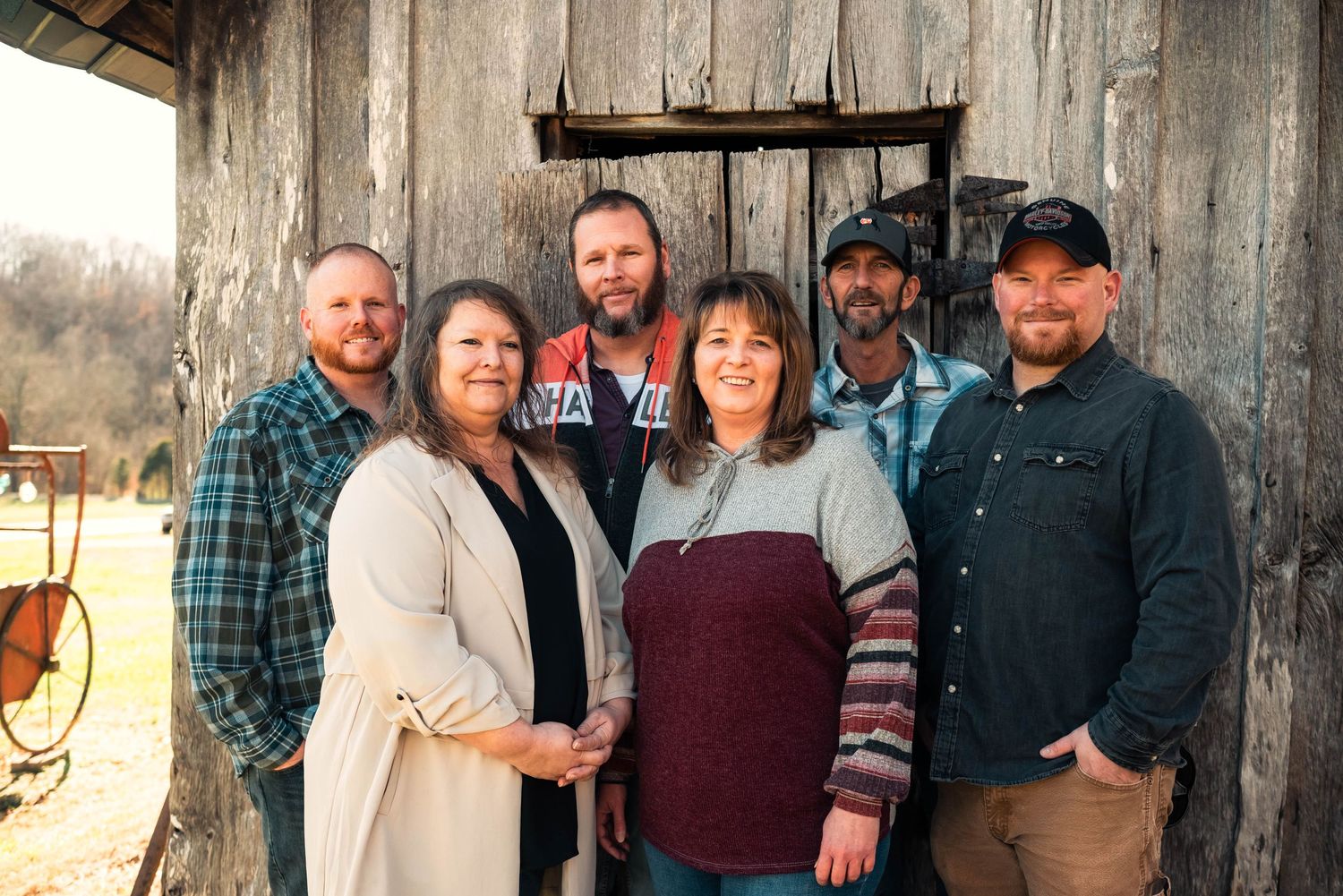 Extended family portrait session against rustic wooden backdrop in casual attire.