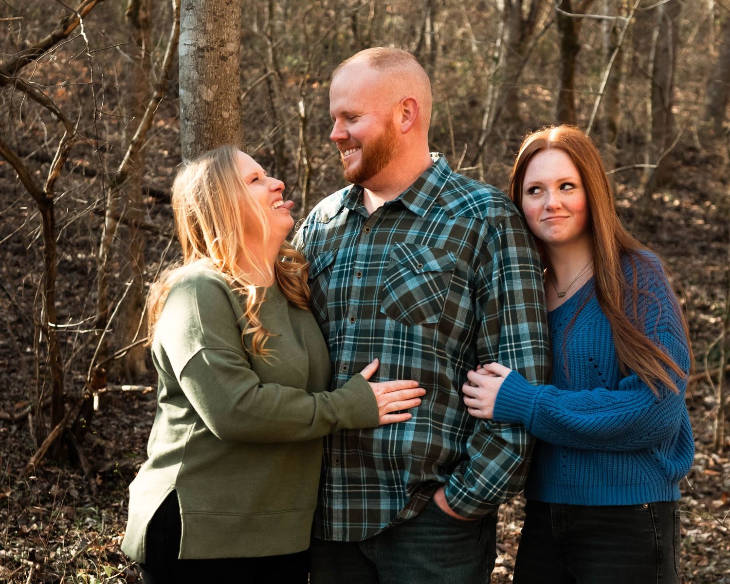 Family members share loving embraces in a wooded outdoor setting during an autumn photo session.
