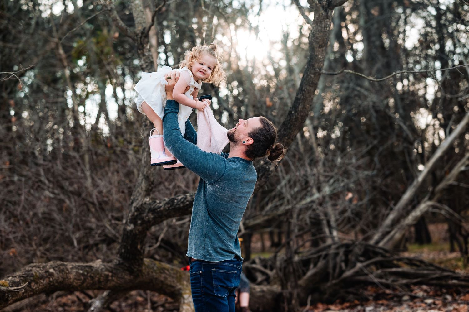 Natural outdoor family photography session among trees and fallen logs.