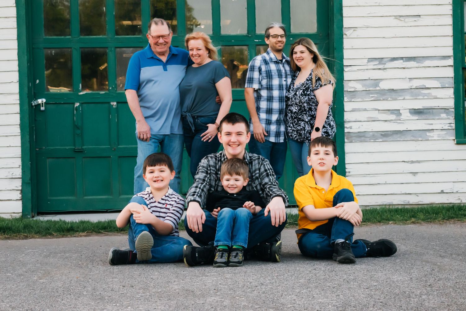 Group photo against rustic white building with green trim and doors.