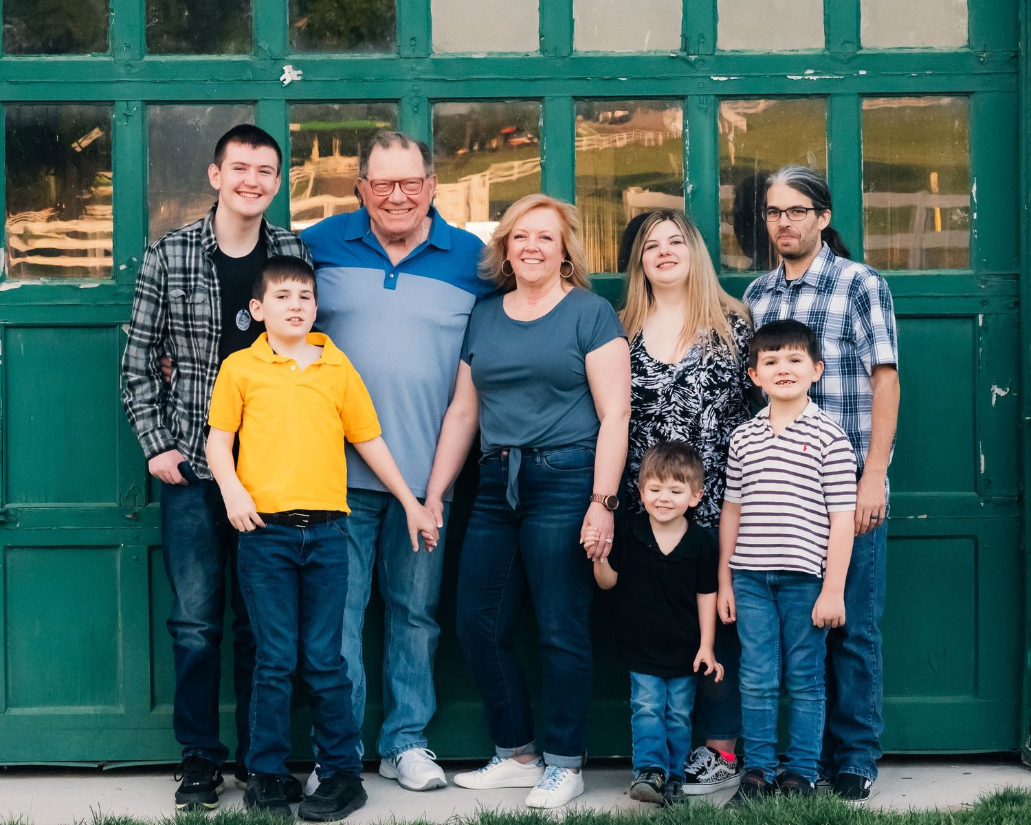Casual family portrait taken in front of vintage building with green doors.