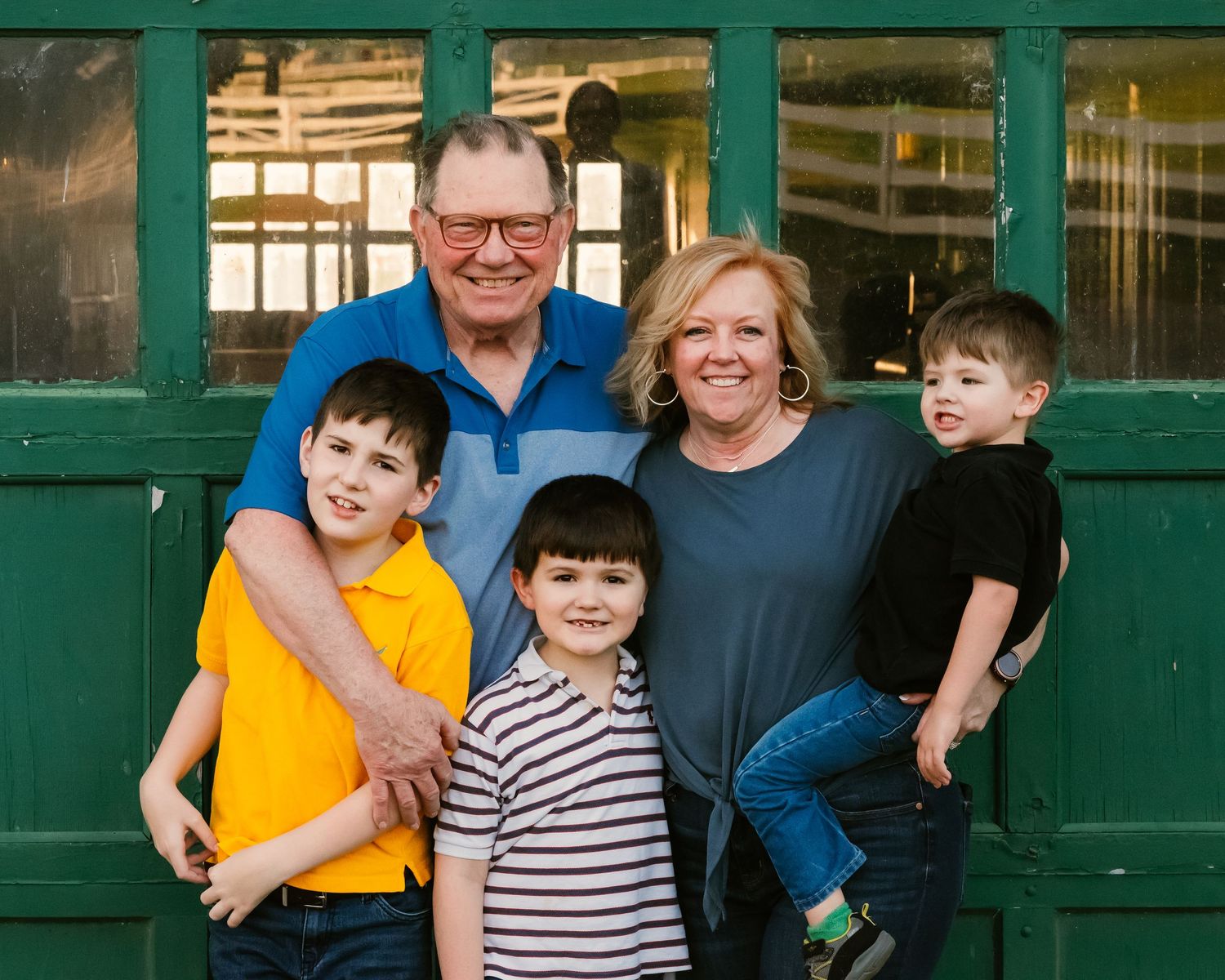 Group photo against vintage building with green doors and window frames.