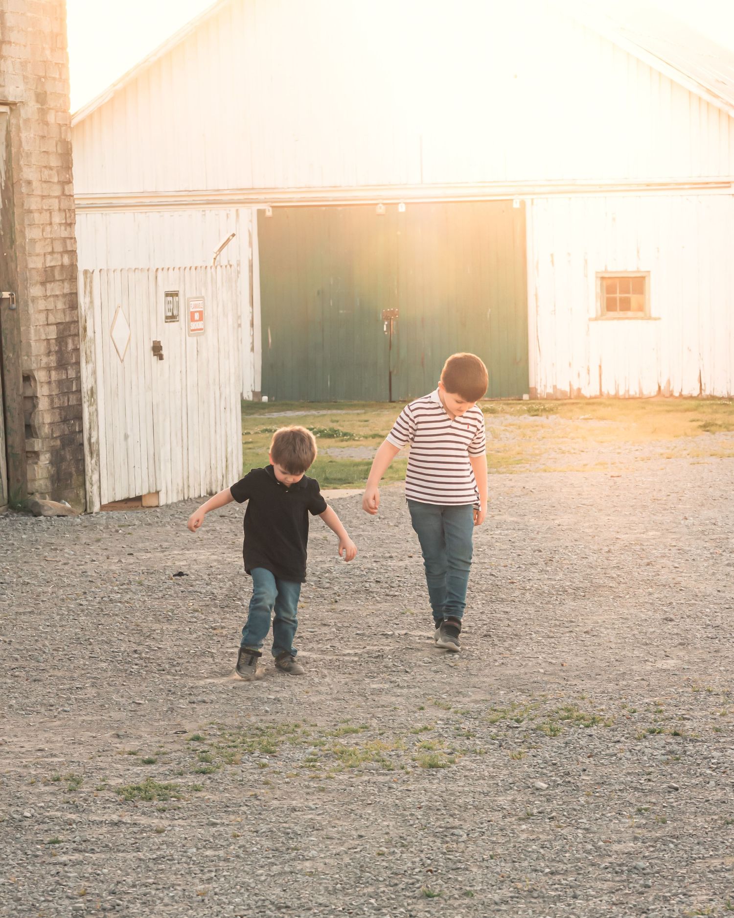 Children walking together at sunset near brick building with warm lighting.