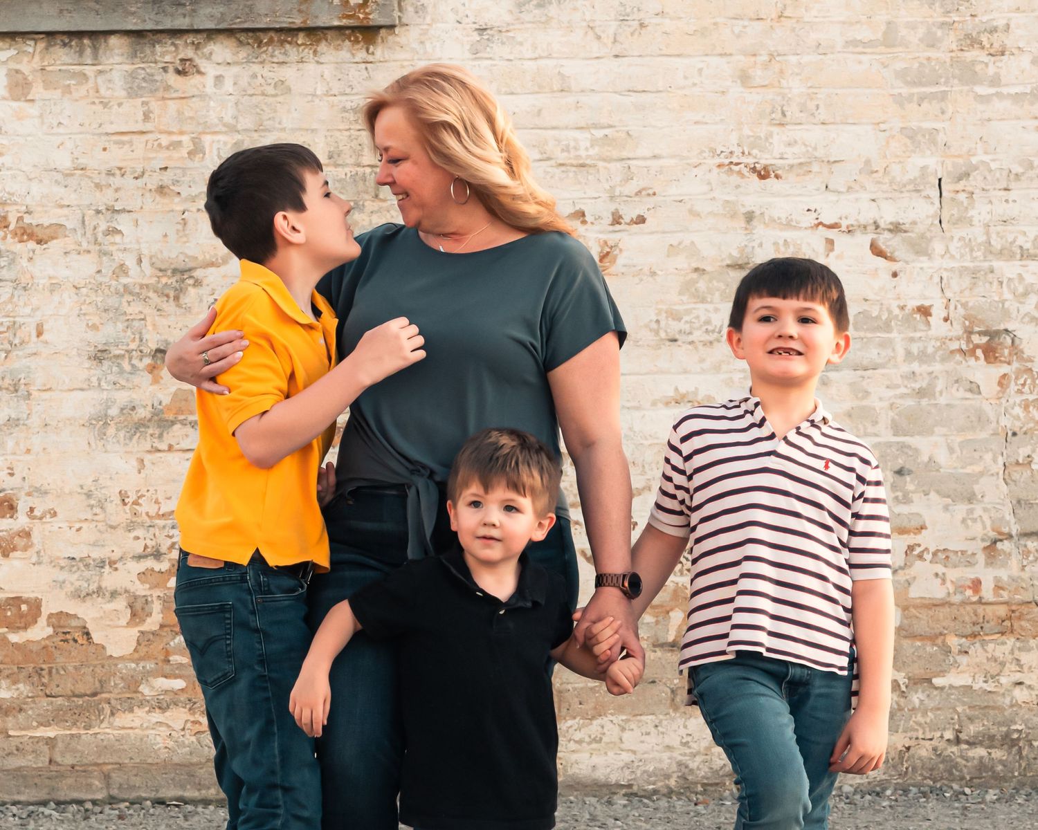 Casual group walking together against weathered brick wall background.