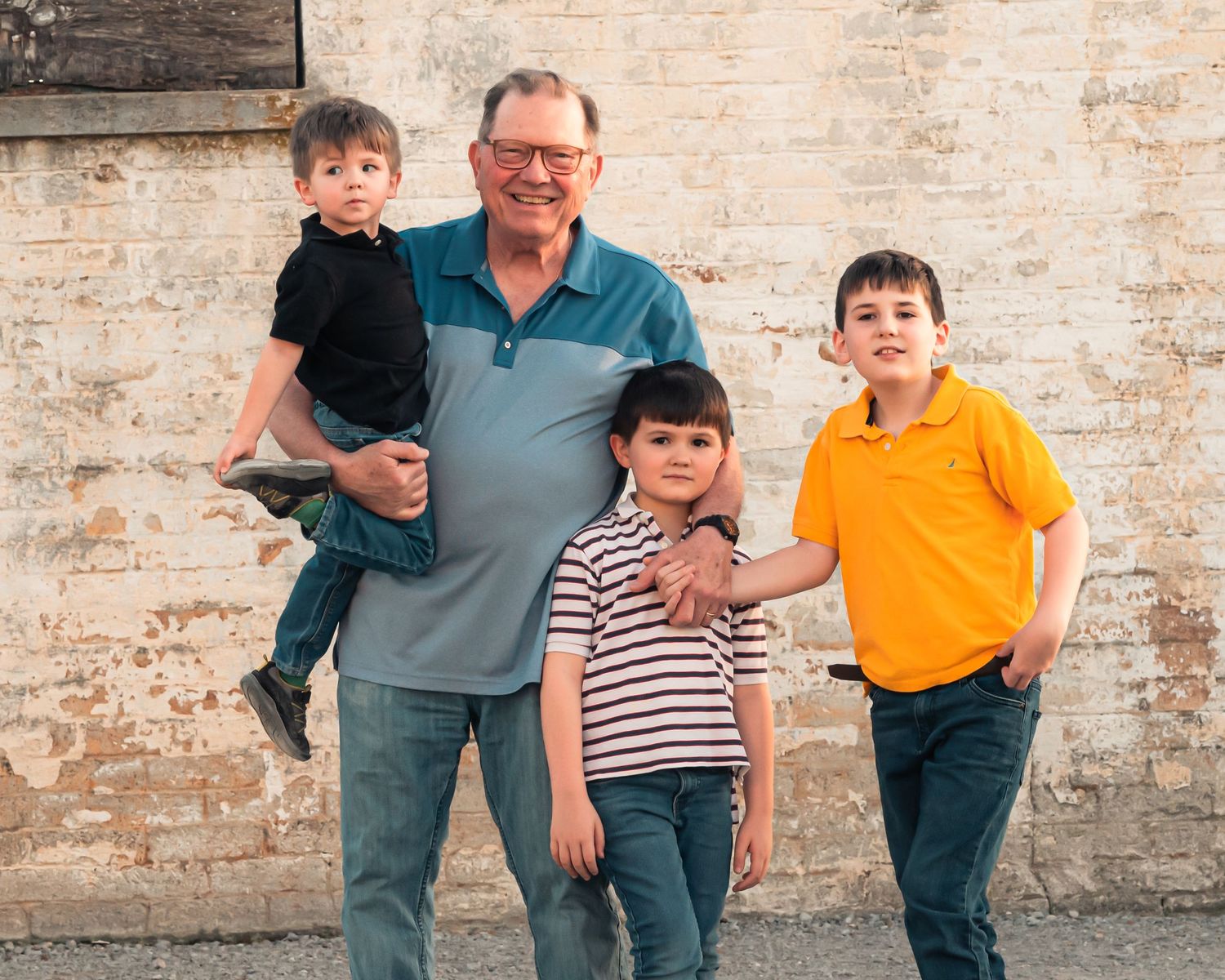 Family portrait session against rustic brick wall backdrop in casual attire.