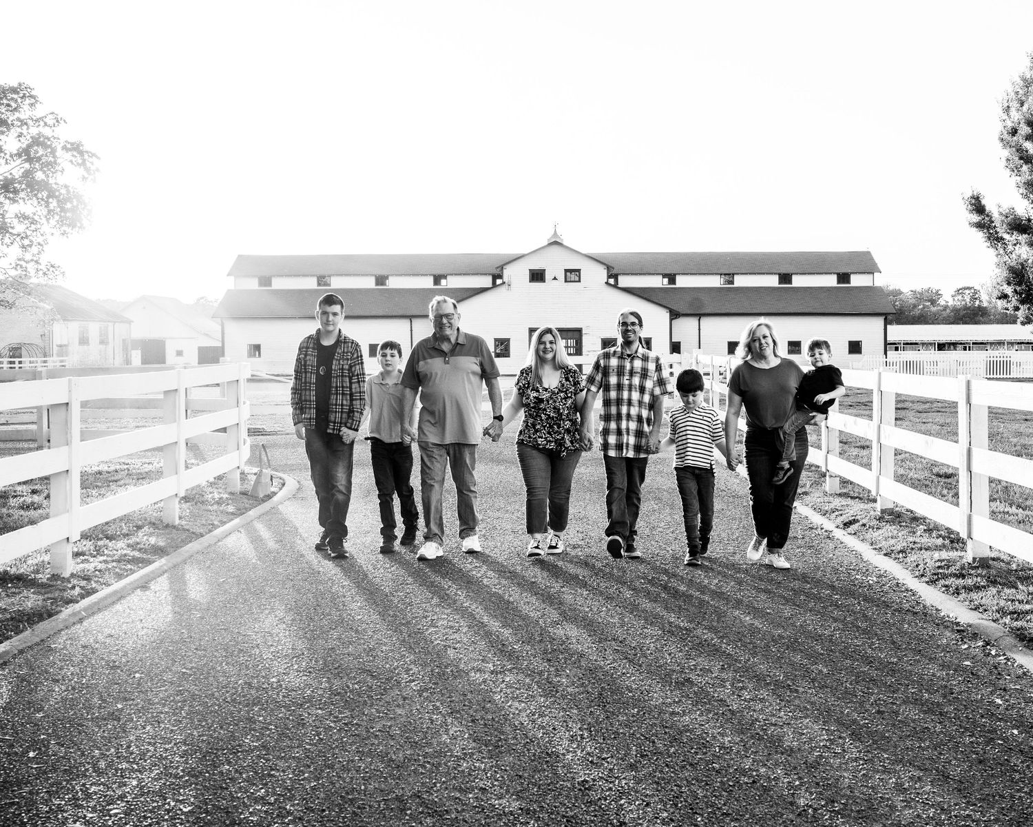Group walking along white fence path in black and white photography.