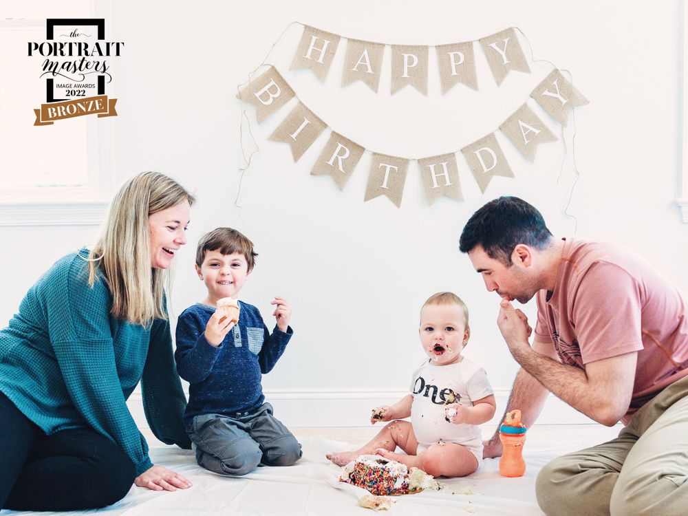 Family gathered around baby during first birthday celebration with cake.