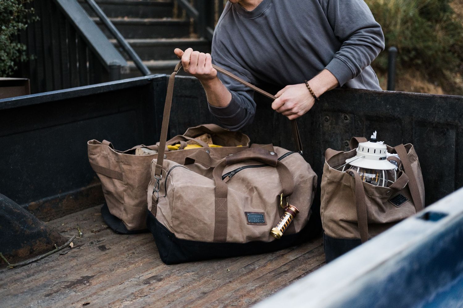 Close-up shots of hands organizing and arranging items in a truck bed or storage area.