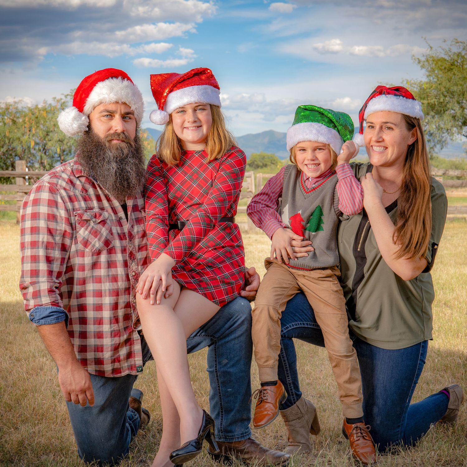 Holiday portrait of family wearing Santa hats posing together outdoors.
