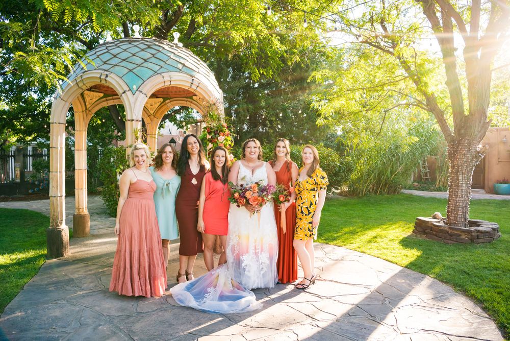 Wedding party poses under a decorative gazebo with turquoise dome on a sunny day.