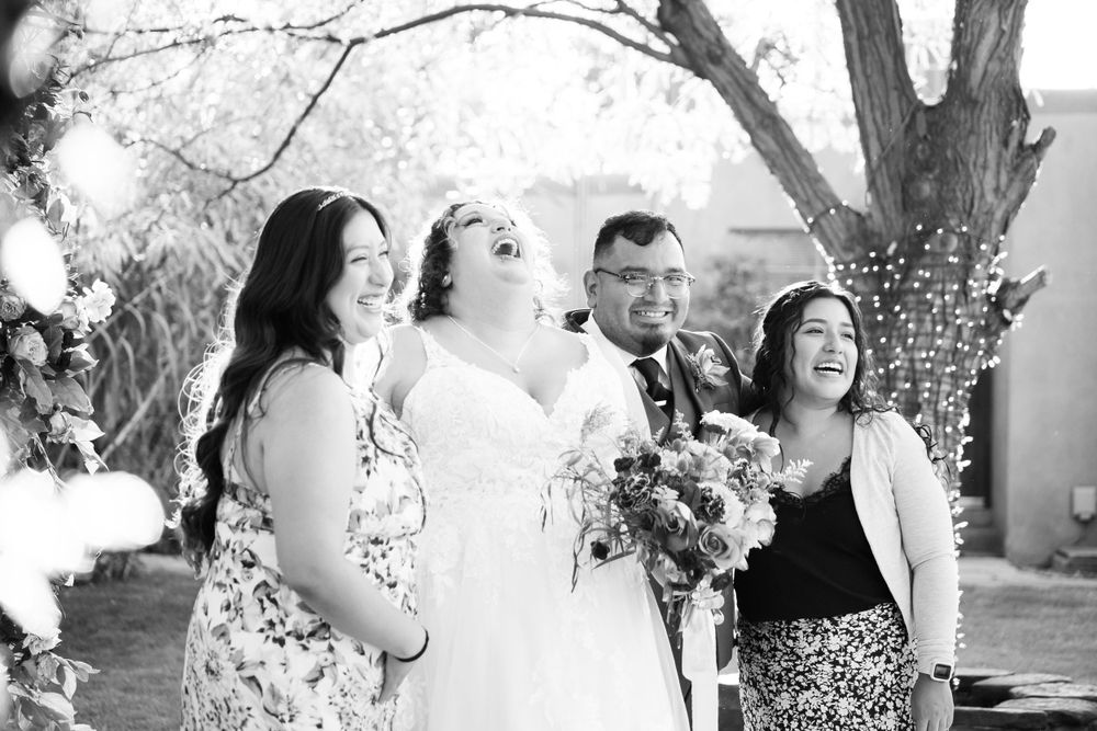 Black and white photo of wedding party sharing a joyful moment outdoors.