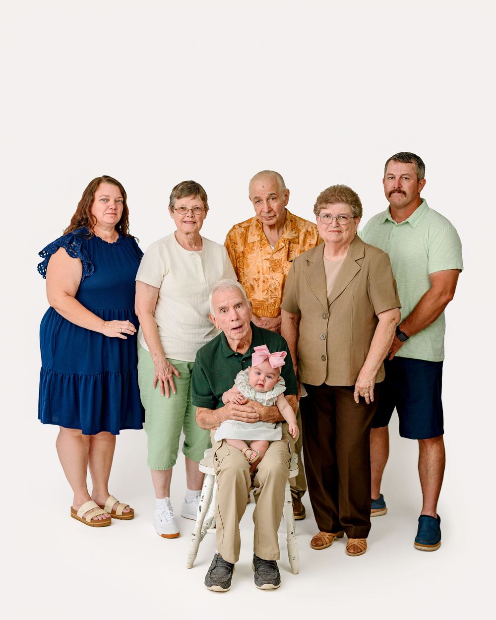 A multi-generational family portrait taken against a white background with six people in casual attire.