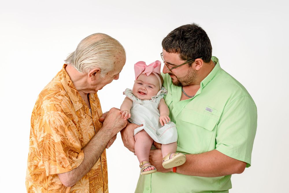Three generations of family members share a tender moment together against a light background.