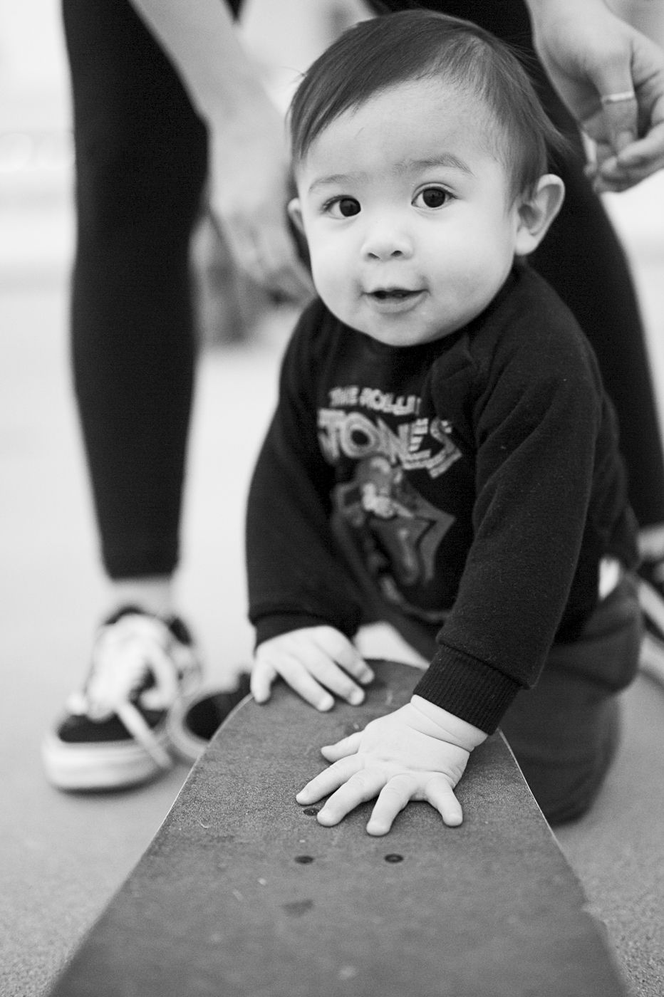 Small child wearing a black graphic sweatshirt leans forward with hands on a surface.