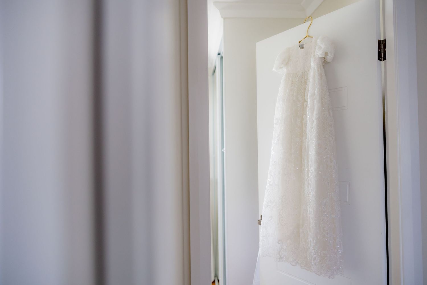 Elegant white dress displayed in doorway with soft focus background.