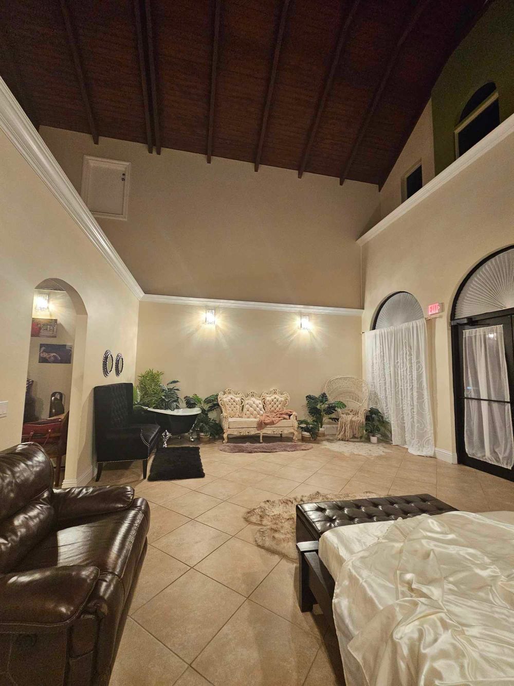 Interior room with vaulted wood ceiling, vintage feel & arched doorways illuminated by wall sconces in a private photo studio in Bonita FL.
