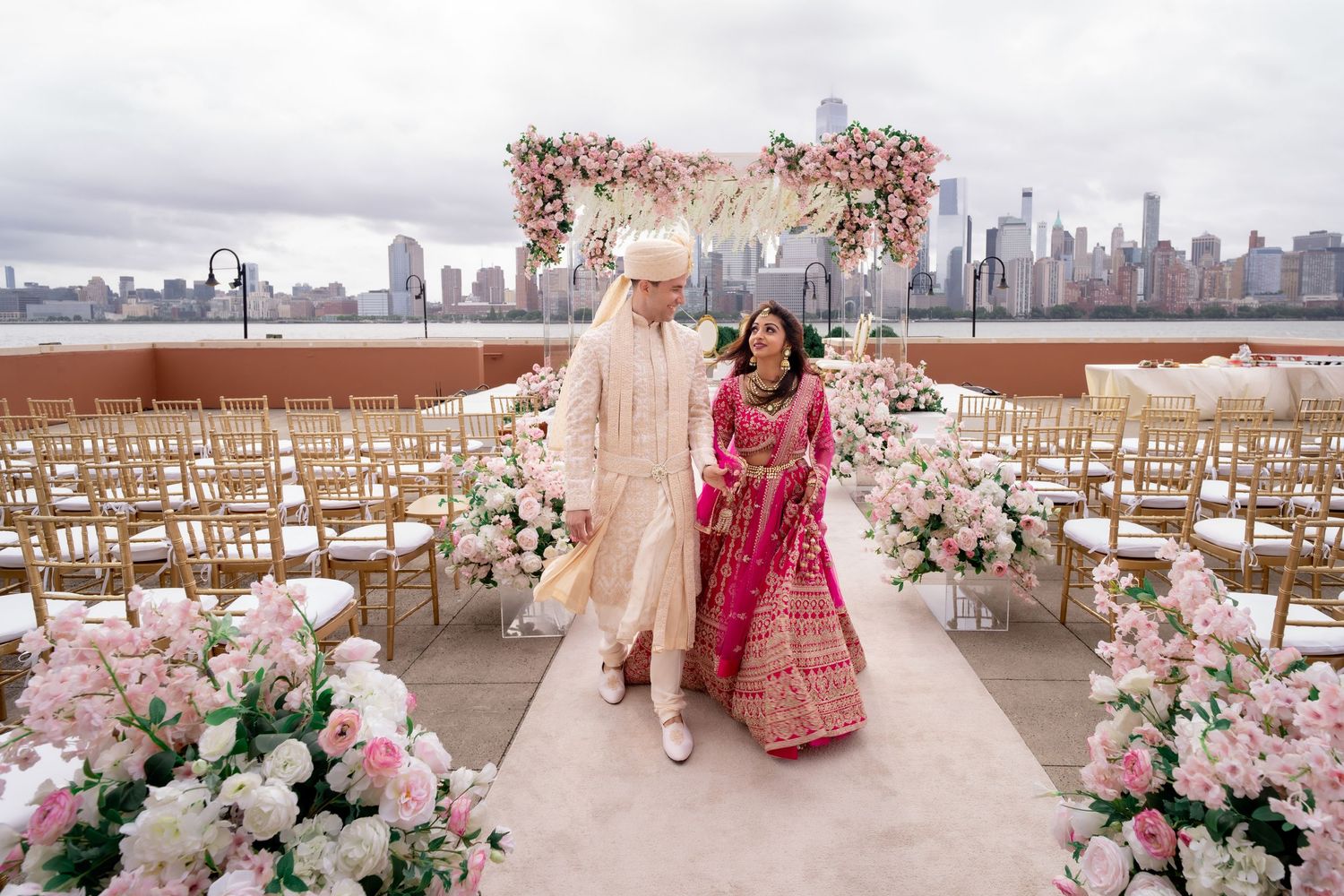 Luxurious outdoor wedding setup with pink floral arrangements and cityscape backdrop.