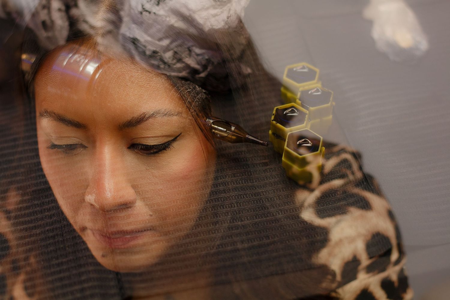 Woman with closed eyes receiving hair treatment with foils and yellow hexagonal clips in a salon.