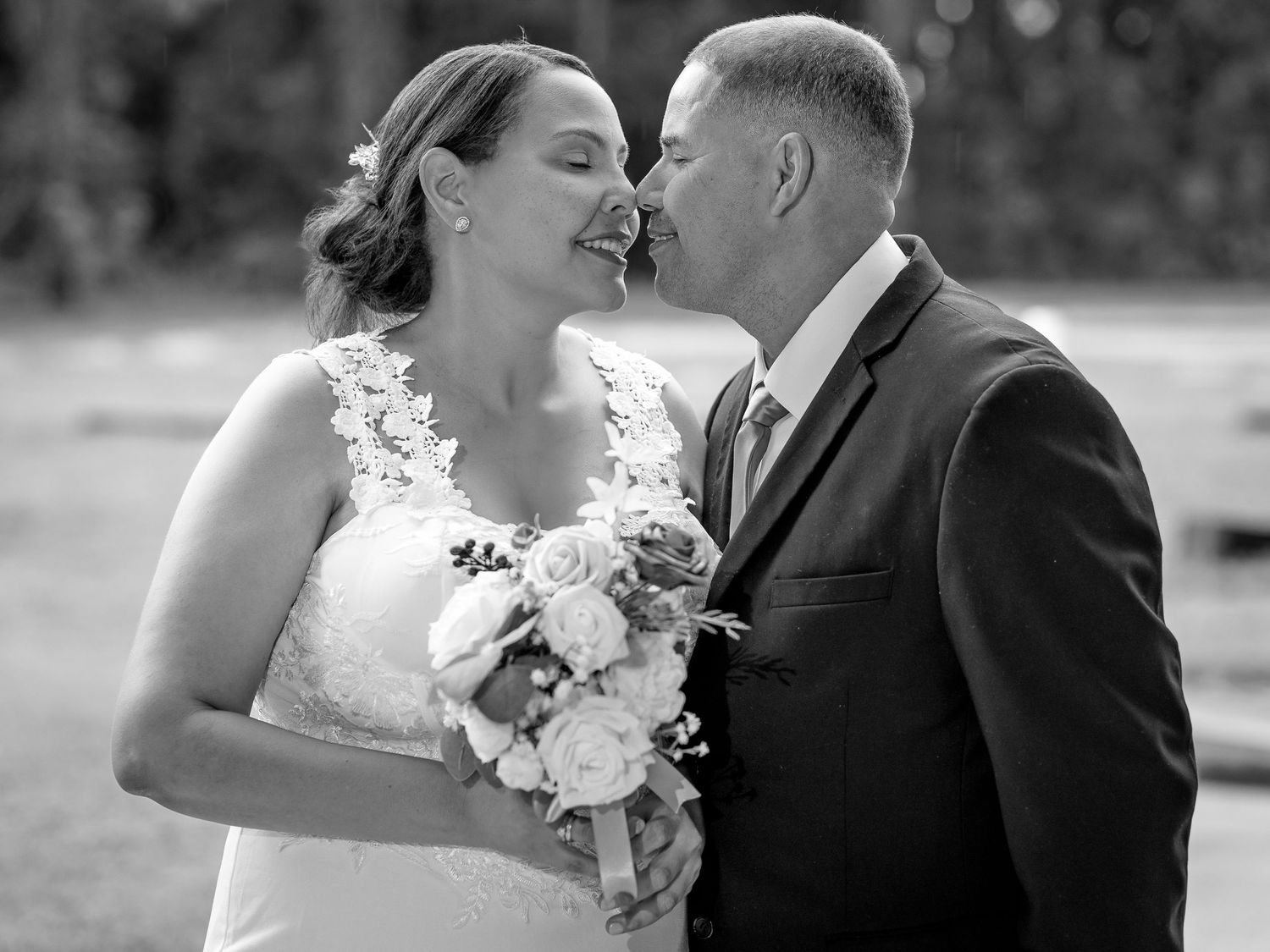 Bride and groom in church with long lace wedding dress and Christmas trees in background.