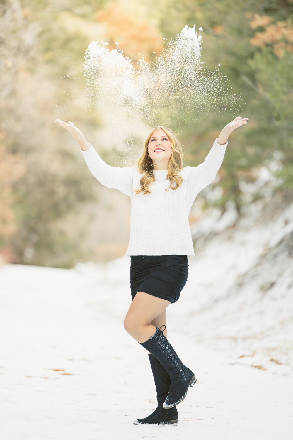 Winter graduation portrait session with girl throwing snow up in whimsical manner by Memorari Portrait