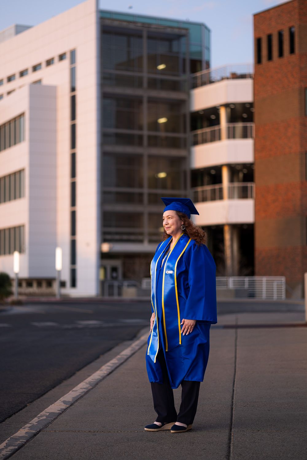Student standing in front of Central New Mexico Community College in cap and gown