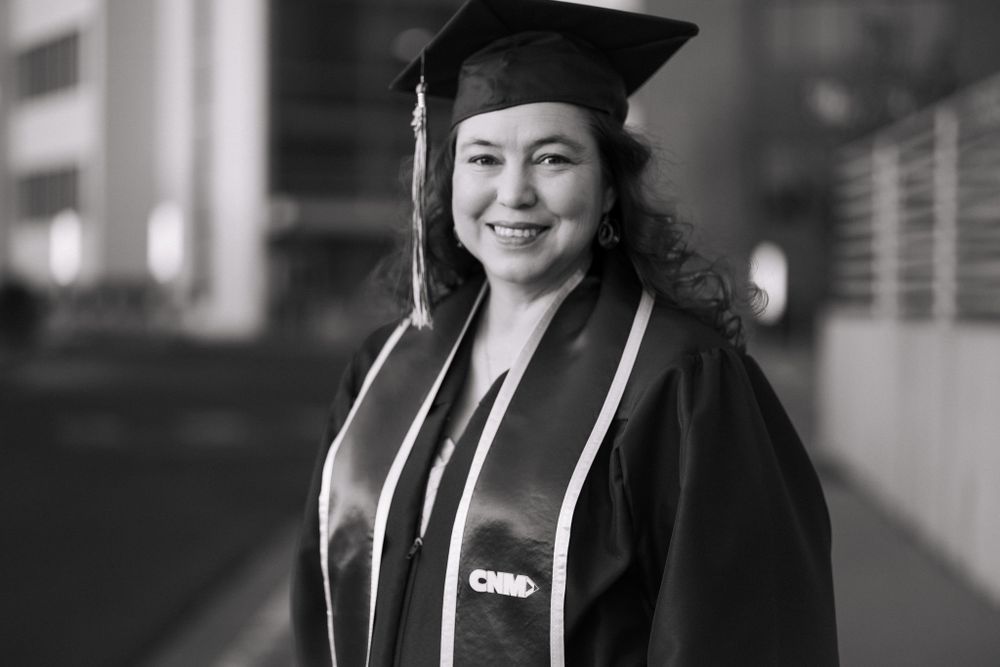 Black and white graduation photo of student in front of Central New Mexico Community College main campus in Albuquerque