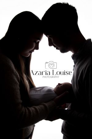 Silhouetted figures looking down at newborn baby in dramatic backlit black and white studio portrait with logo.
