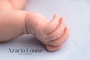 Close-up black and white photo of a tiny baby foot with curled toes against a soft light background.