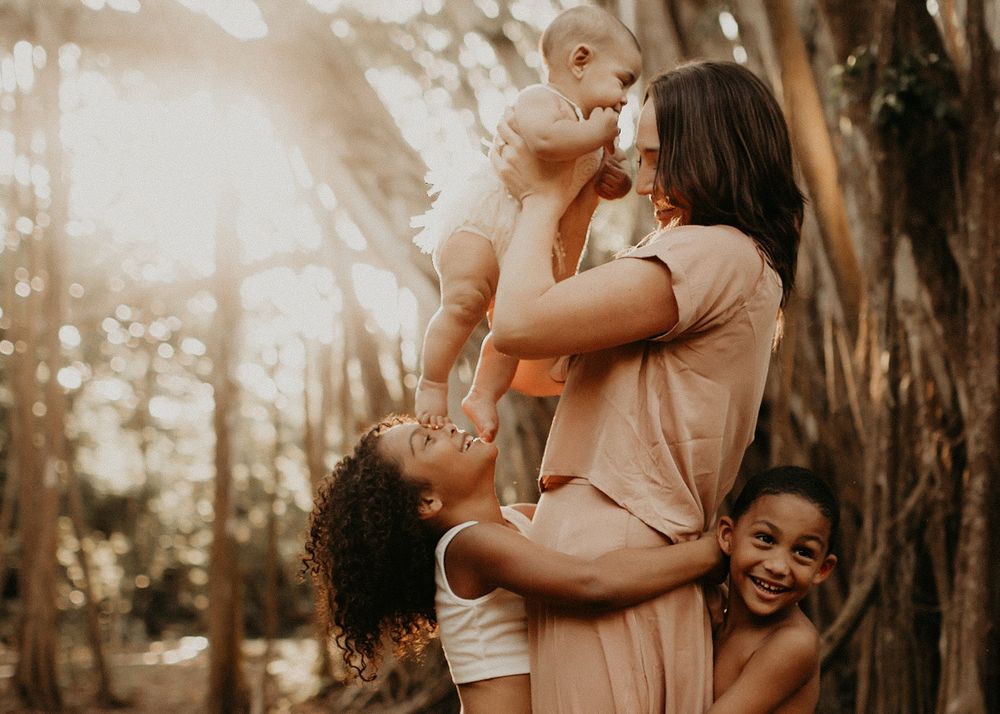 Family portrait session in a sunlit forest with warm tones.