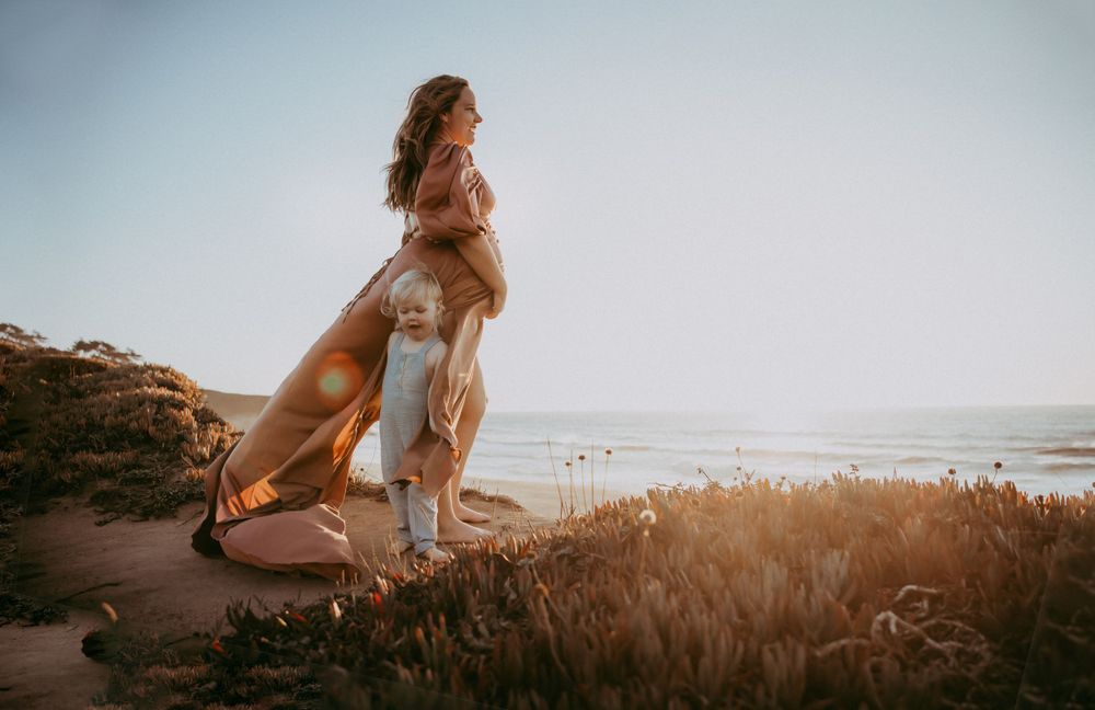Family beach photoshoot during golden hour with ocean waves in the background.